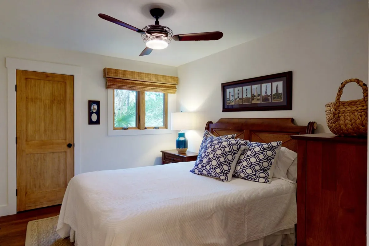 A bright, peaceful bedroom with a bed adorned with patterned pillows, wooden furniture, and a window allowing sunlight to stream in. The atmosphere is serene and inviting, ideal for restful sleep.