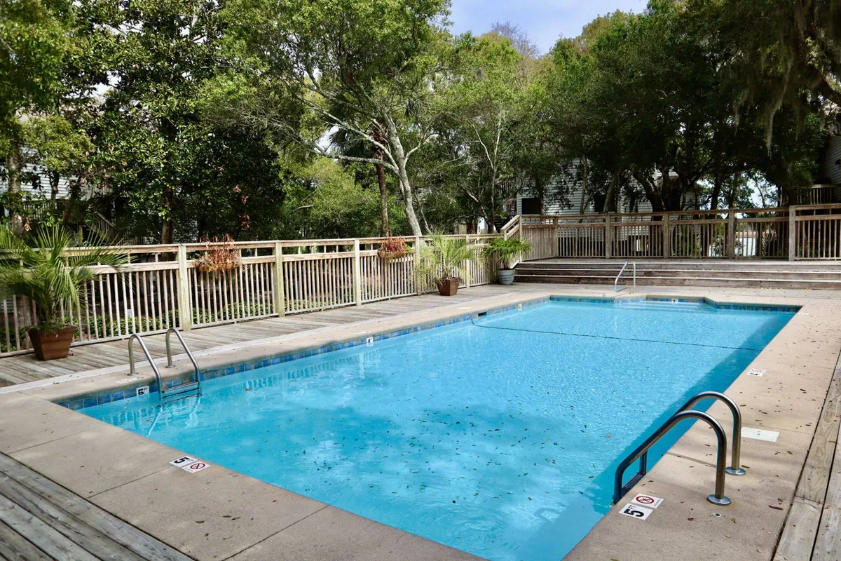 A sparkling swimming pool surrounded by lush greenery and a deck area, inviting guests for a swim or relaxation. The tranquil environment suggests a serene community amenity available for use.