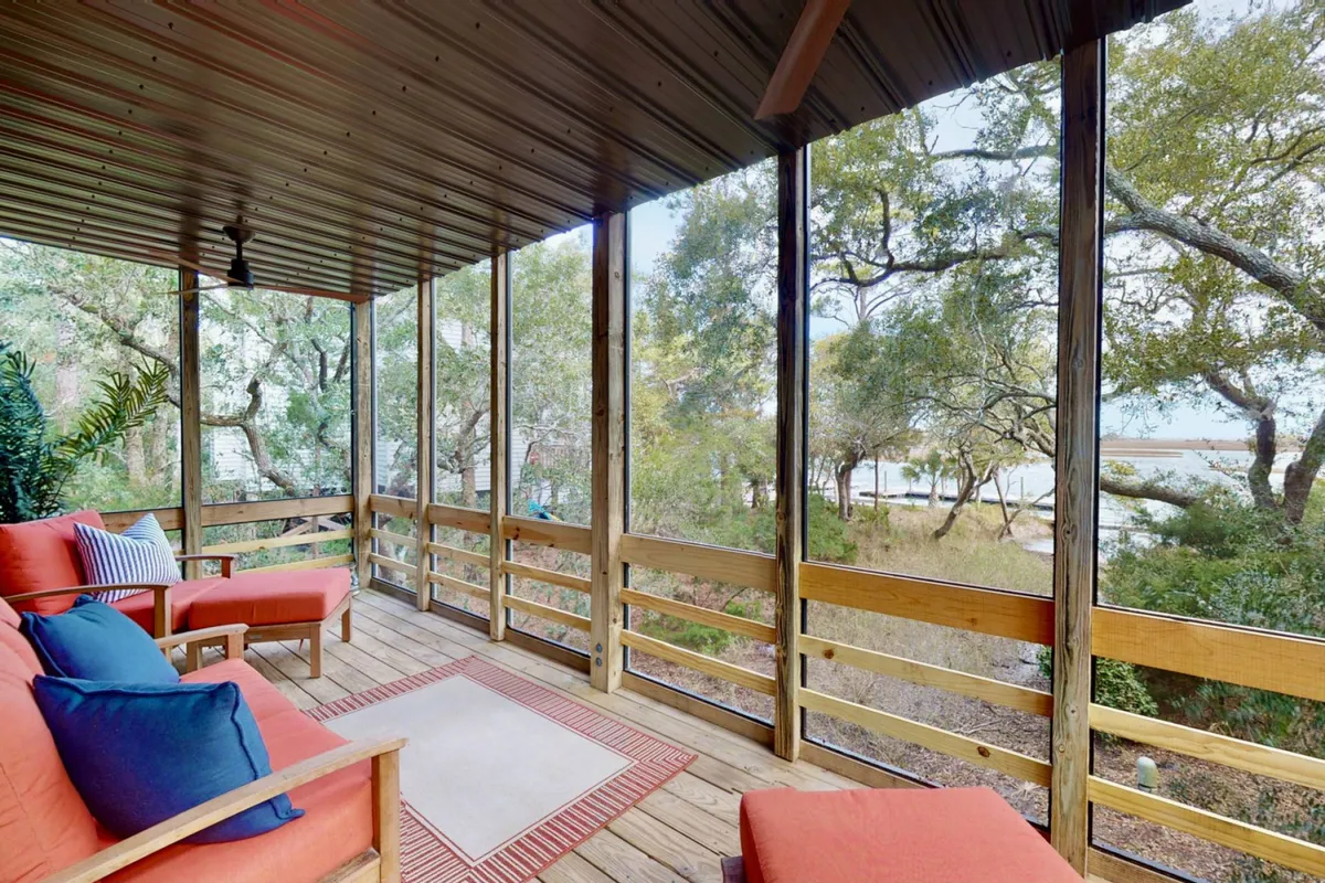 A bright, inviting living area with plush seating is framed by expansive windows offering serene marsh views. The soft morning light pours in, creating a tranquil space perfect for unwinding, reading, or savoring your coffee while immersed in nature's beauty.